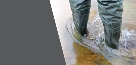 Person in rubber waders walking through water that goes above their ankles