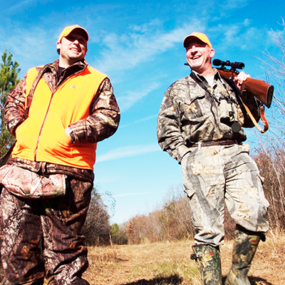 Two men walking with a rifle slung over their shoulders