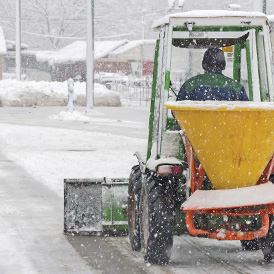 utility vehicle clearing snow and spreading salt on a snowy day